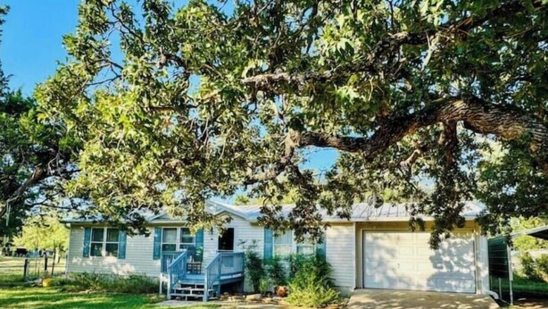 Una casa de un nivel con porche delantero, garaje y un pequeño jardín con césped y un sendero de grava.