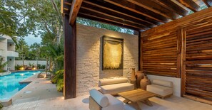 Une terrasse extérieure avec un mur en pierre, des meubles en bois et une piscine.