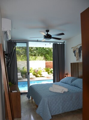 Une chambre avec un lit, un ventilateur de plafond et une vue sur une piscine.