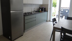 Una cocina moderna con refrigerador, estufa y armarios. Hay una mesa de comedor con sillas y vistas al exterior a través de una puerta corrediza de vidrio.