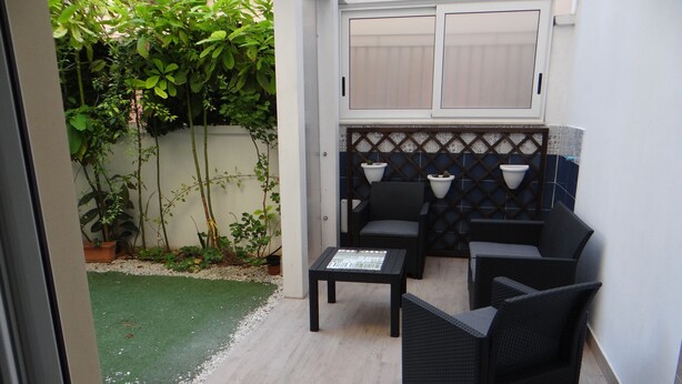Un patio con muebles de mimbre, una pequeña mesa y un revoque de azulejos.