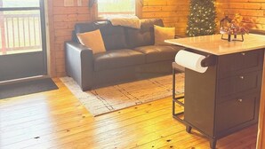 L’intérieur chaleureux d’un chalet avec un plancher en bois, un canapé en cuir, un petit sapin de Noël et un meuble en bois.