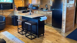 L'intérieur d'un chalet en bois comprend une cuisine, un coin bar et un espace détente avec des sièges.