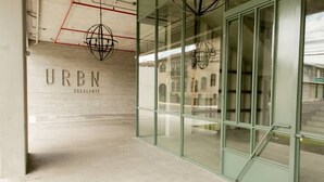 A modern interior with a glass wall, a concrete wall with text, and hanging spherical light fixtures. - Miravé San José Escalante (San Jose)