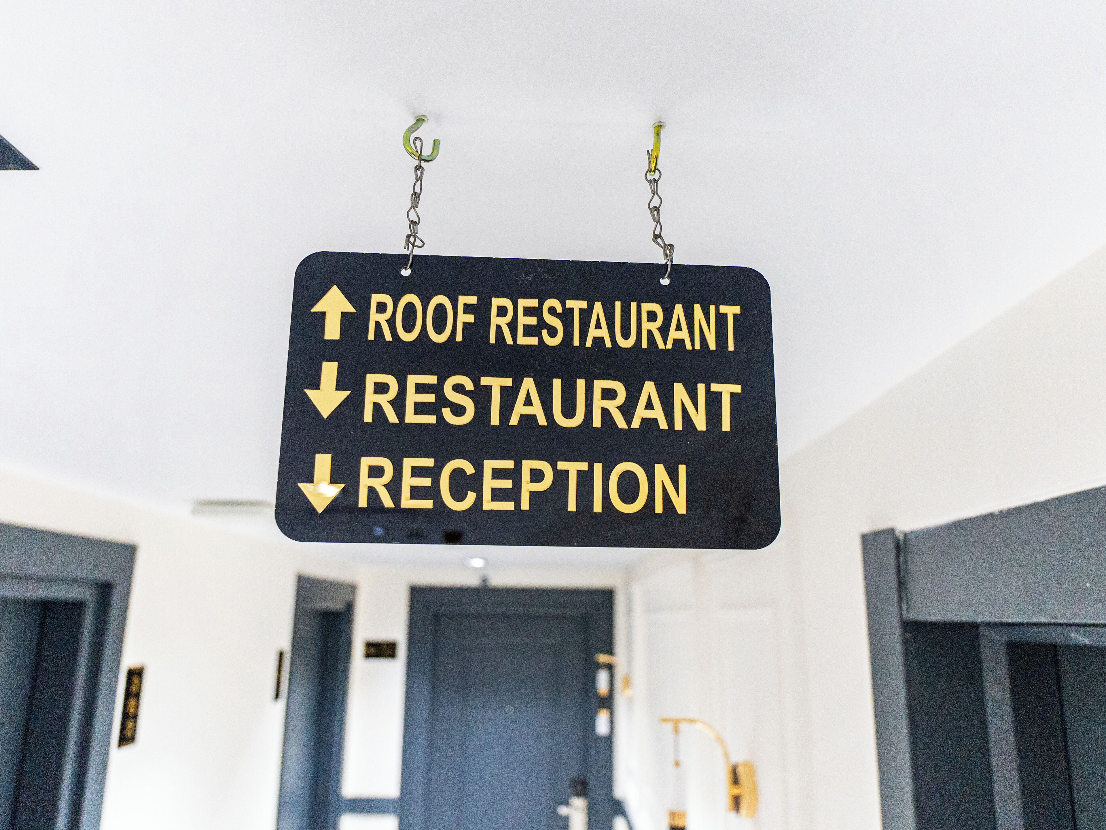 A directional sign with arrows pointing to 'ROOF RESTAURANT,' 'RESTAURANT,' and 'RECEPTION.'