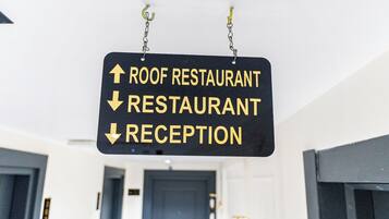 A directional sign with arrows pointing to 'ROOF RESTAURANT,' 'RESTAURANT,' and 'RECEPTION.'