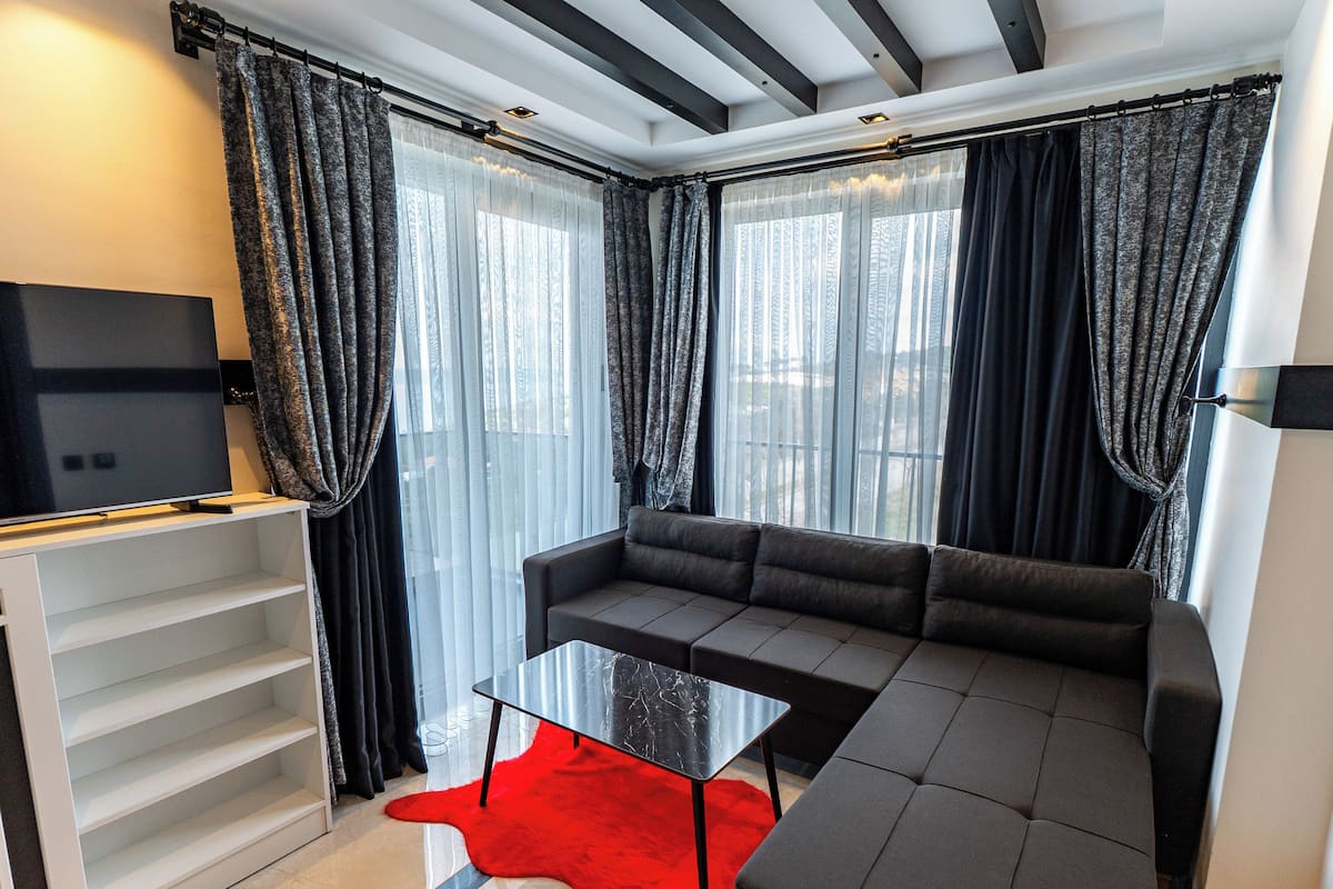 Ein modernes Wohnzimmer mit Ecksofa, Flachbildfernseher und Couchtisch mit Glasplatte.