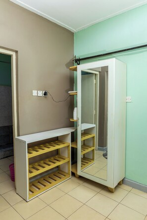Una habitación con un armario blanco, un espejo y una estantería.