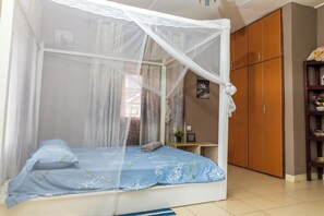 Un dormitorio con cama con dosel, armario de madera y una mesita de noche con una planta.