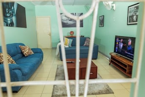 A living room with two sofas, a coffee table, a TV, and a fan.