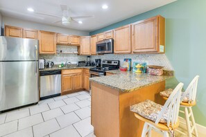 A kitchen with wooden cabinets, stainless steel appliances, a granite countertop, and a ceiling fan. - 4 Mi to Siesta Key Beach: Condo w/ Pool Access (Sarasota)