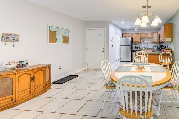 A dining area with a round table, white chairs, and a wooden cabinet. - 4 Mi to Siesta Key Beach: Condo w/ Pool Access (Sarasota)
