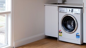Une buanderie équipée d’un lave-linge, d’un évier et d’un tableau encadré accroché au mur.
