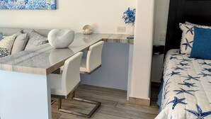 A modern room with a sofa, a small table, a desk, and a bed with a starfish pattern. - Brand New Listing: Elegant Studio Suite with Ocean and Pool View (Cabo San Lucas)