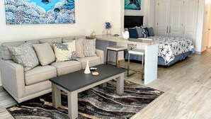 A modern living room with a sofa, coffee table, and artwork depicting marine life. - Brand New Listing: Elegant Studio Suite with Ocean and Pool View (Cabo San Lucas)