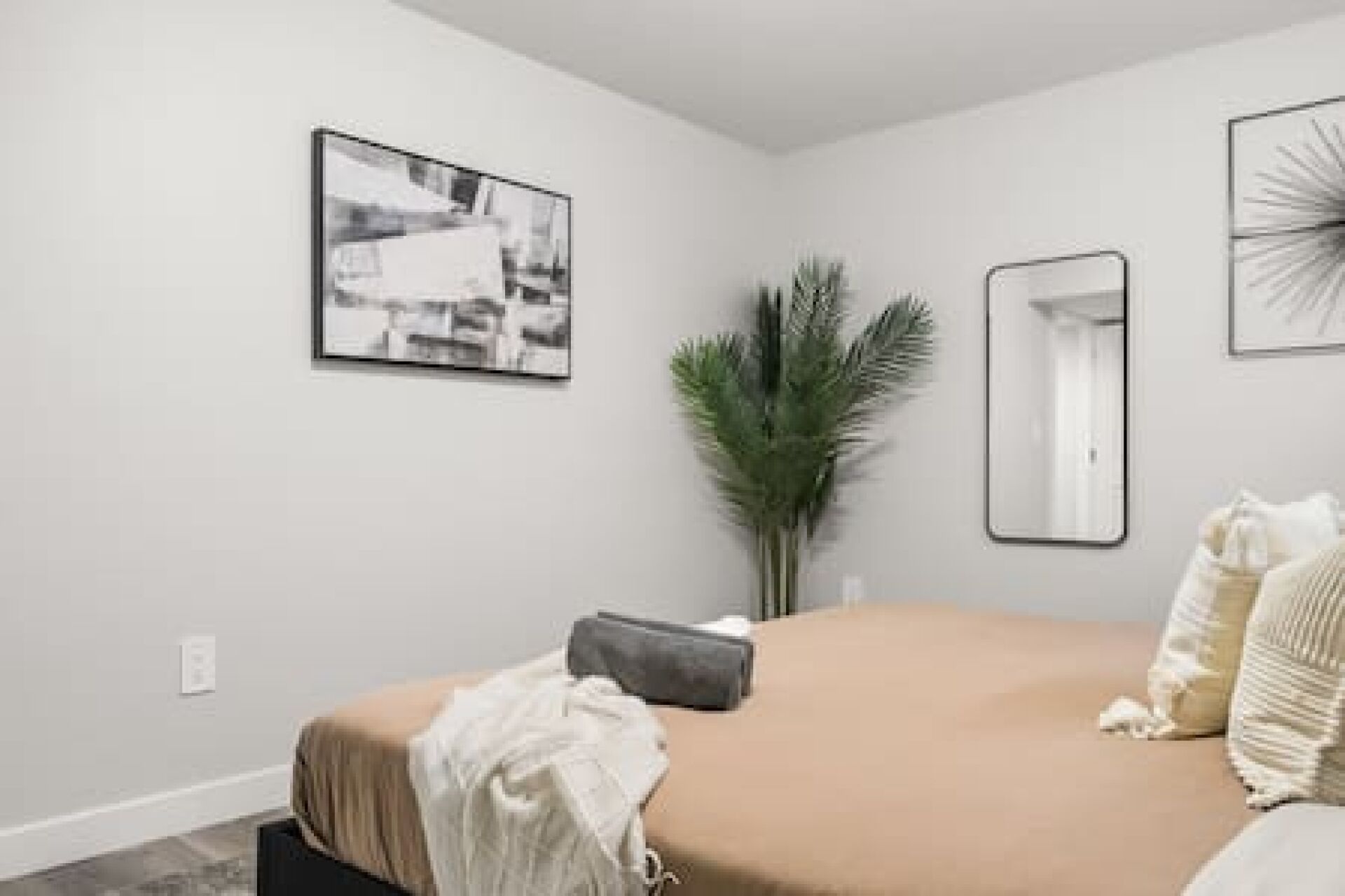 Une chambre à coucher avec un lit, un miroir et un tableau encadré accroché au mur.