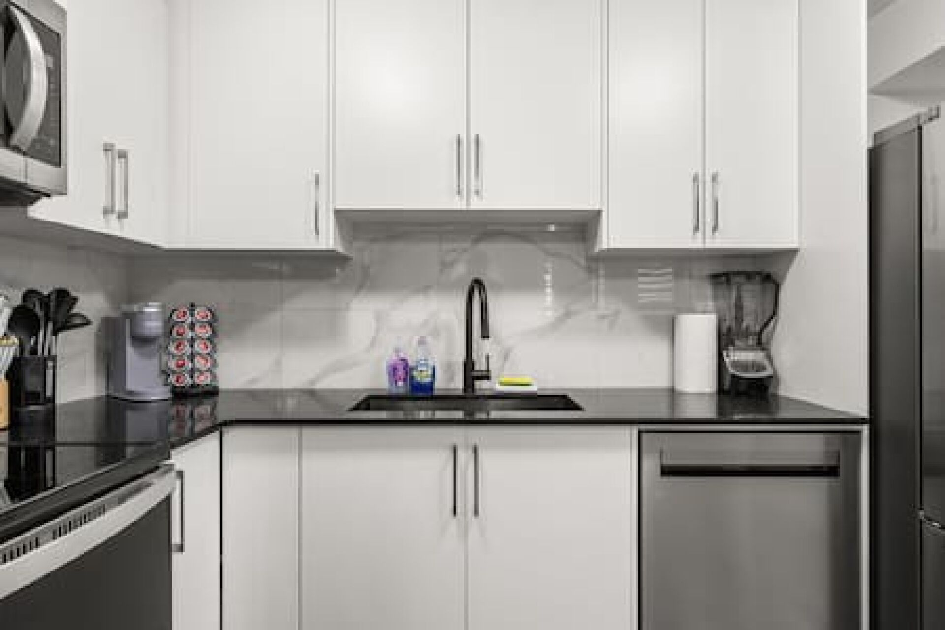 A modern kitchen with white cabinets, a stainless steel sink, and a dishwasher.