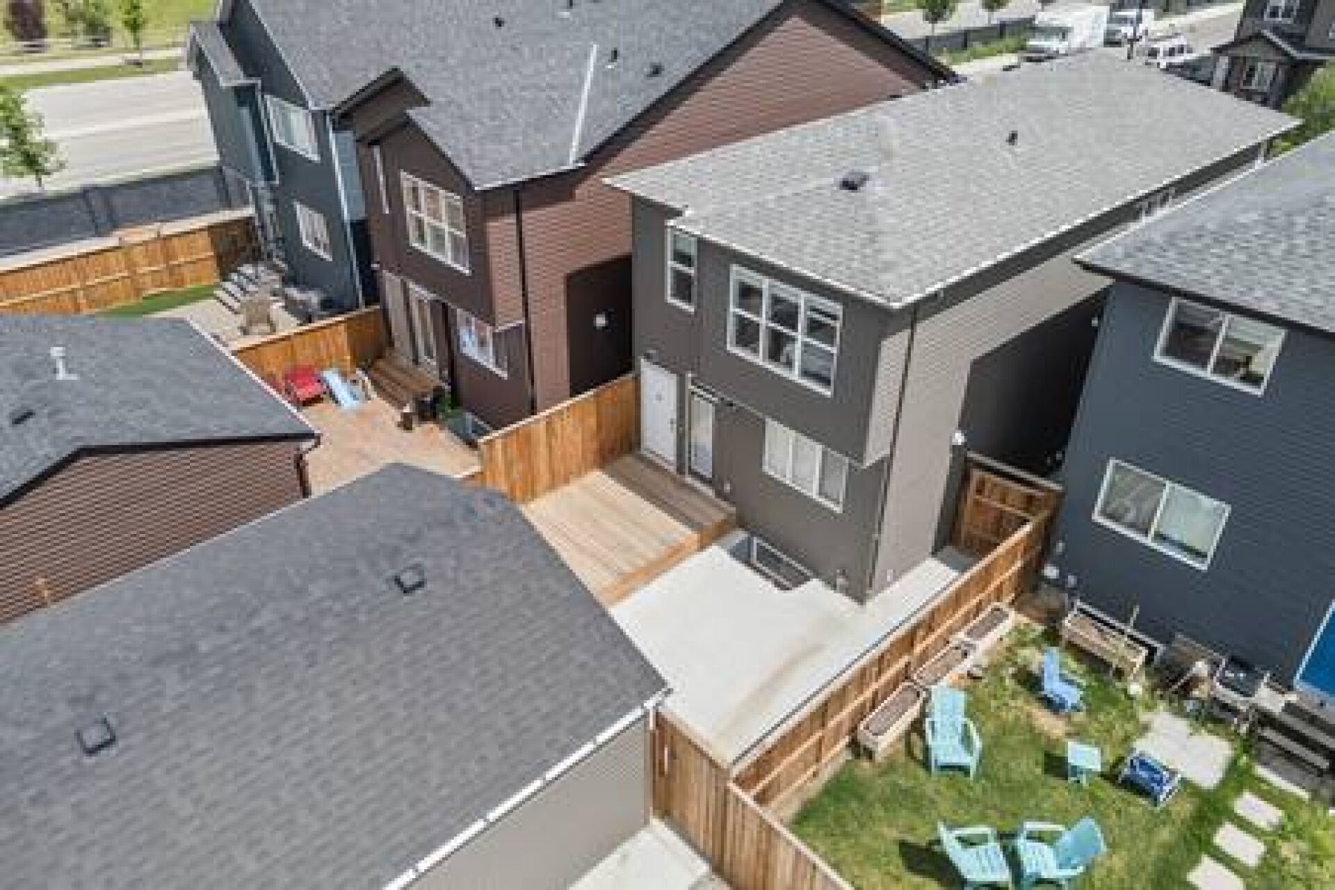 A residential area with modern houses, a wooden deck, and outdoor seating.