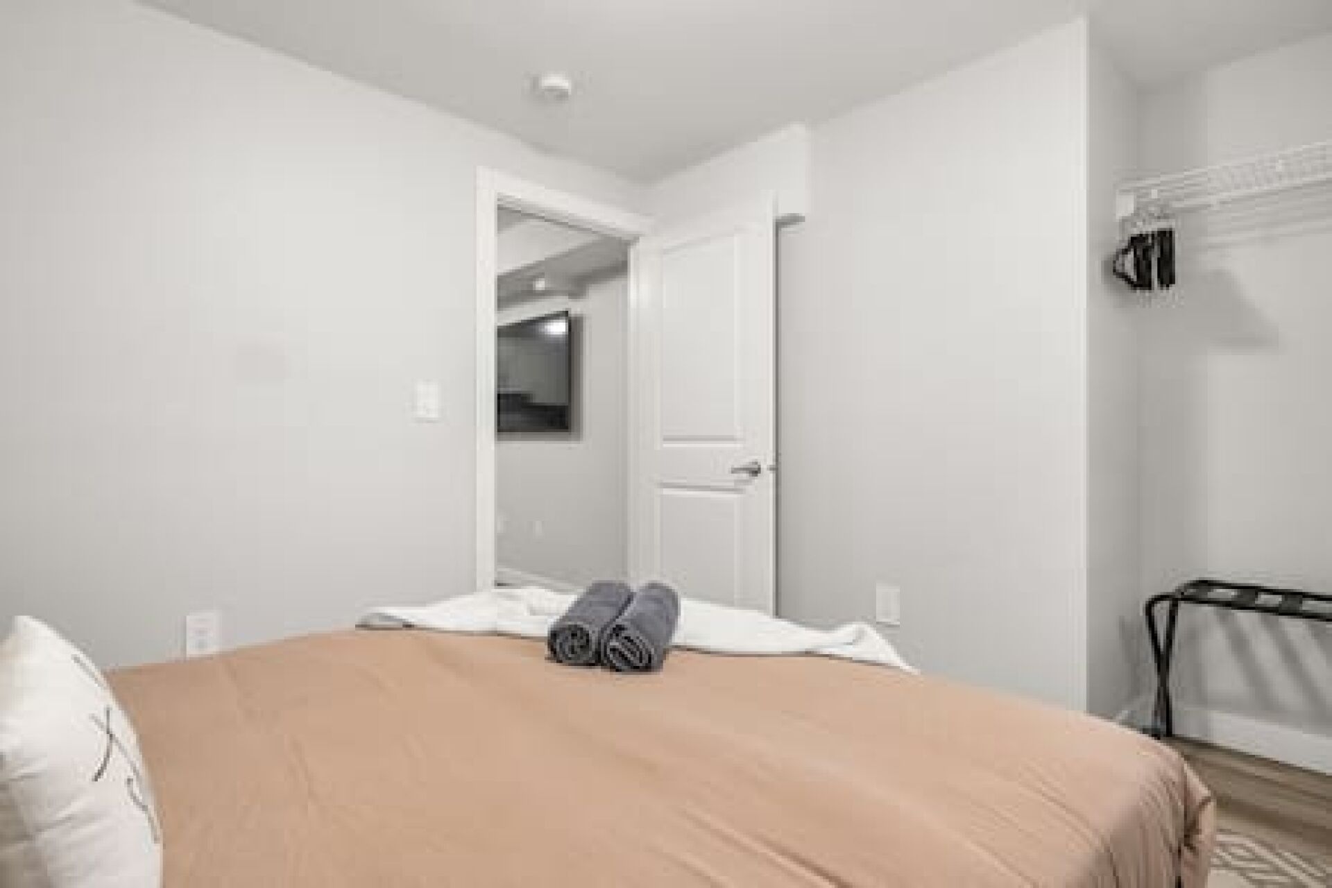 Una camera da letto con un letto, una porta che dà su un'altra stanza e un appendiabiti.