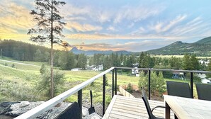 Une terrasse offrant une vue sur un paysage rural, avec des maisons et une chaîne de montagnes.