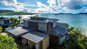 A coastal property with multiple buildings, a clear view of the sea, and lush greenery. - ABSOLUTE WATERFRONT LUXURY WITH NEW BUGGY (Hamilton Island)