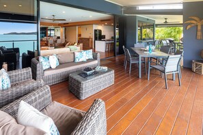 A spacious outdoor living area with wicker furniture, a dining table, and chairs. - ABSOLUTE WATERFRONT LUXURY WITH NEW BUGGY (Hamilton Island)