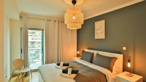 Ein Hotelzimmer mit Bett, Sessel, Nachttisch, Lampe und Blick ins Freie.