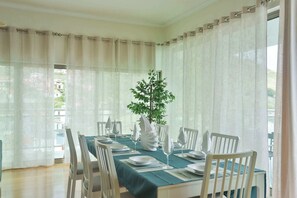 A dining area with a table set for four, white chairs, and a potted plant.
