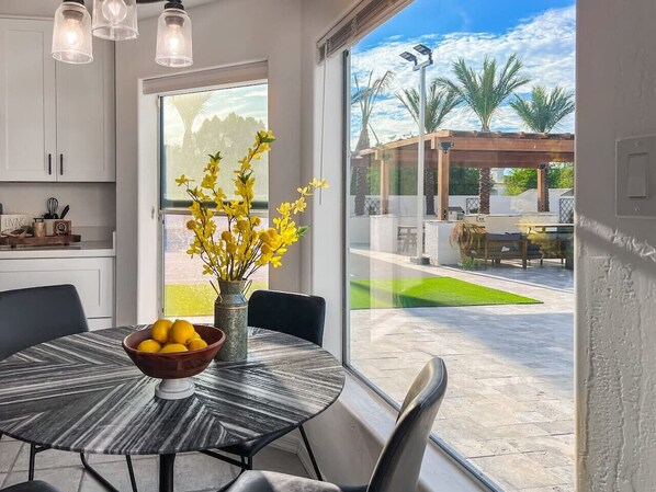 Une cuisine moderne avec une table à manger, un bol de citrons et un vase de fleurs jaunes.