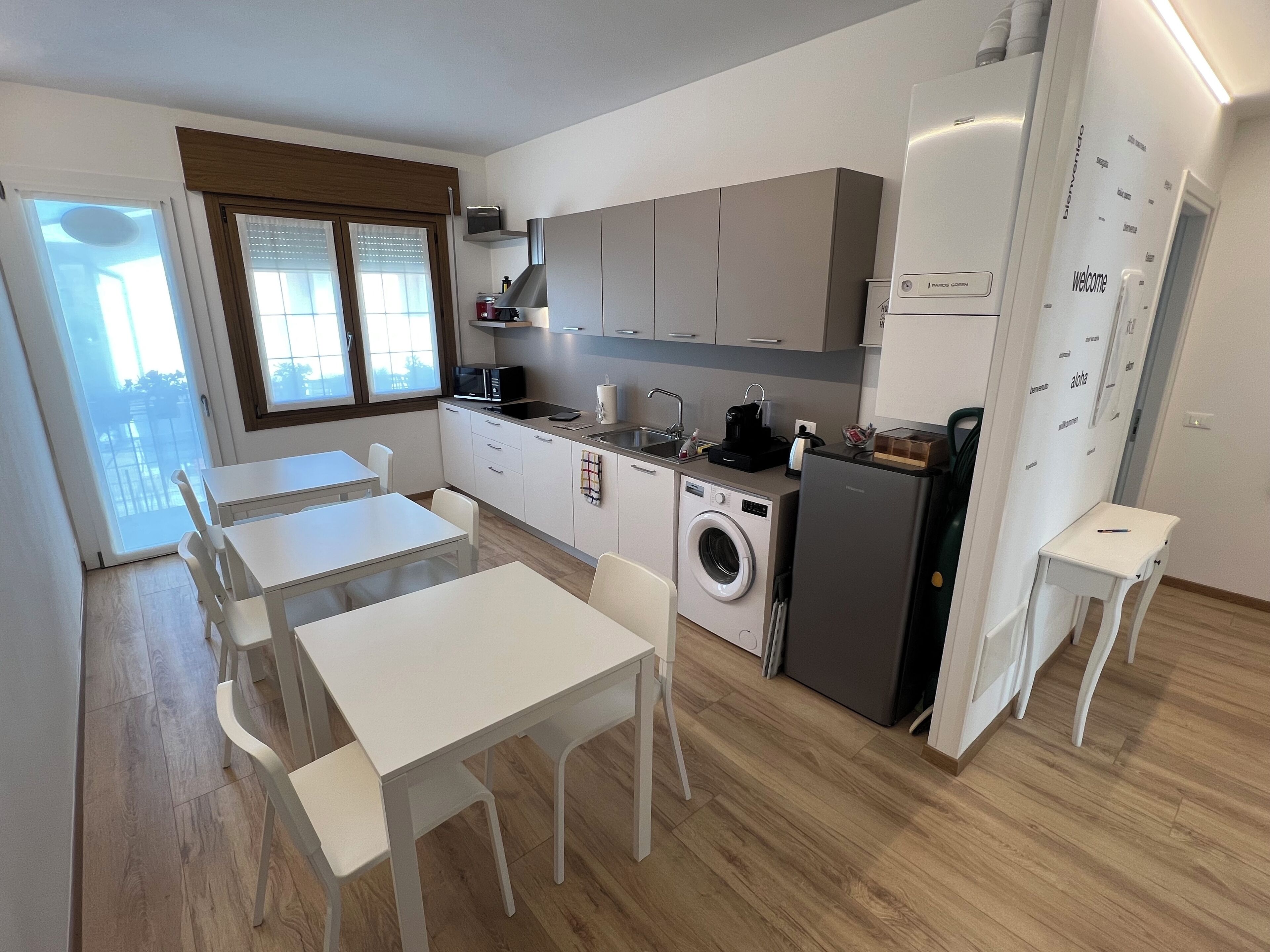 Eine kleine Küche mit Waschmaschine, Kühlschrank und einem Essbereich mit weißer Möbel.