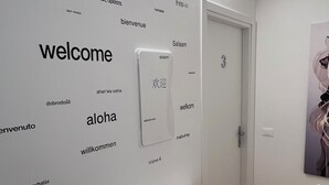A hallway with a white reception desk, a wall with multilingual 'welcome' signs, and a door labeled 'Salaam'. - Ceciaìs House ROOM 2 (Bassano del Grappa)