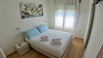 A neatly made bed with blue pillows, a small bedside table with a lamp, and a wall-mounted artwork.