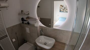 A bathroom with a white sink, a mirror, and a shower.