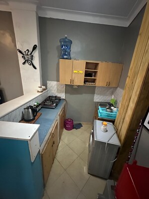 A compact kitchen with a gas stove, a sink, and wooden cabinets.