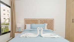Una cama con una colcha azul y dos almohadas blancas con forma de cisne.