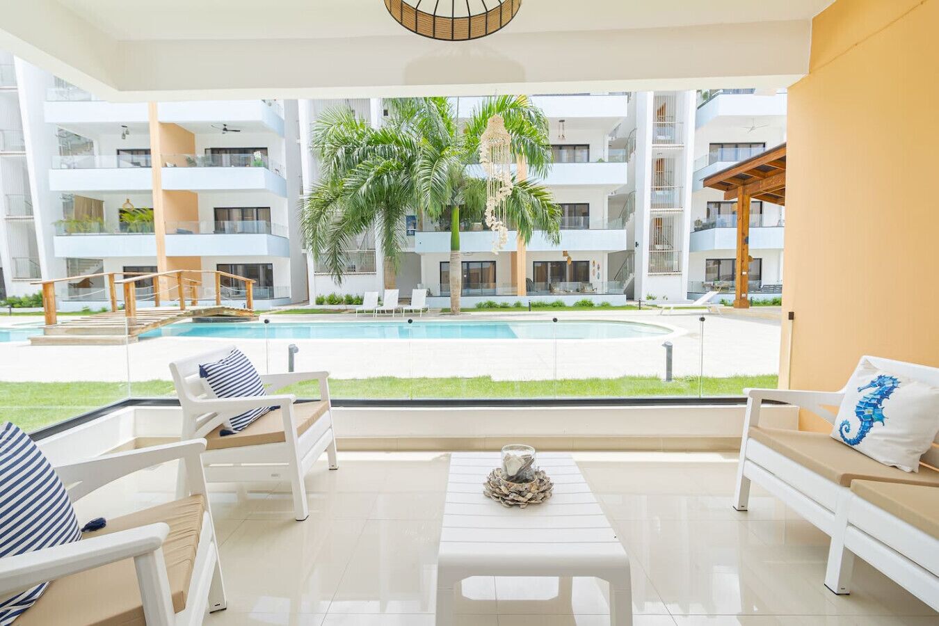 A modern hotel room with a pool view, white furniture, and a tropical garden.