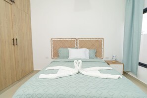 Ein Hotelzimmer mit Bett, Schrank, Nachttisch und einem Fenster mit Vorhängen.