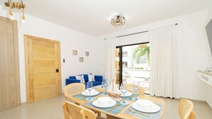 Un comedor con una mesa de madera dispuesta para cuatro, un sofá azul y vistas al exterior.