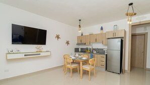 Una cocina moderna con armarios de madera, un refrigerador de acero inoxidable y un comedor con mesa y sillas.