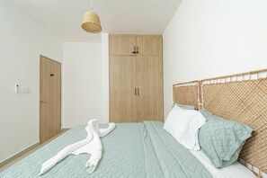 A bedroom with a bed, a wardrobe, and a hanging light fixture.