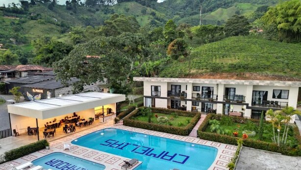 A hotel with a swimming pool, outdoor seating, and a view of the surrounding hills.