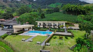 A hotel with a swimming pool, a tennis court, and a view of the surrounding hills.