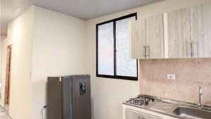 A kitchen with a refrigerator, stove, sink, and wooden cabinets.