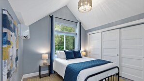 A bedroom with a bed, a window, a door, and a wall-mounted air conditioner. - Lakefront-Hot Tub, 2 Kitchens, Kayaks, Game Room (Bremerton)