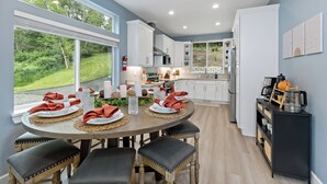 A modern kitchen with white cabinets, a dining area with a round table and chairs, and a view of the outdoors. - Lakefront-Hot Tub, 2 Kitchens, Kayaks, Game Room (Bremerton)