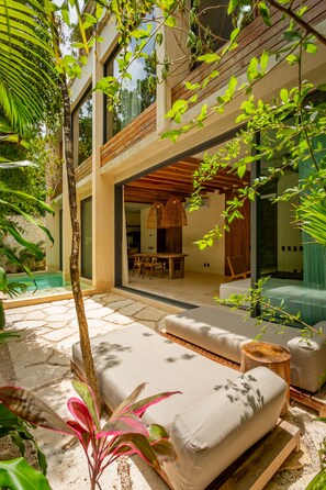 A modern outdoor living area with a pool, lounge chairs, and a dining area.