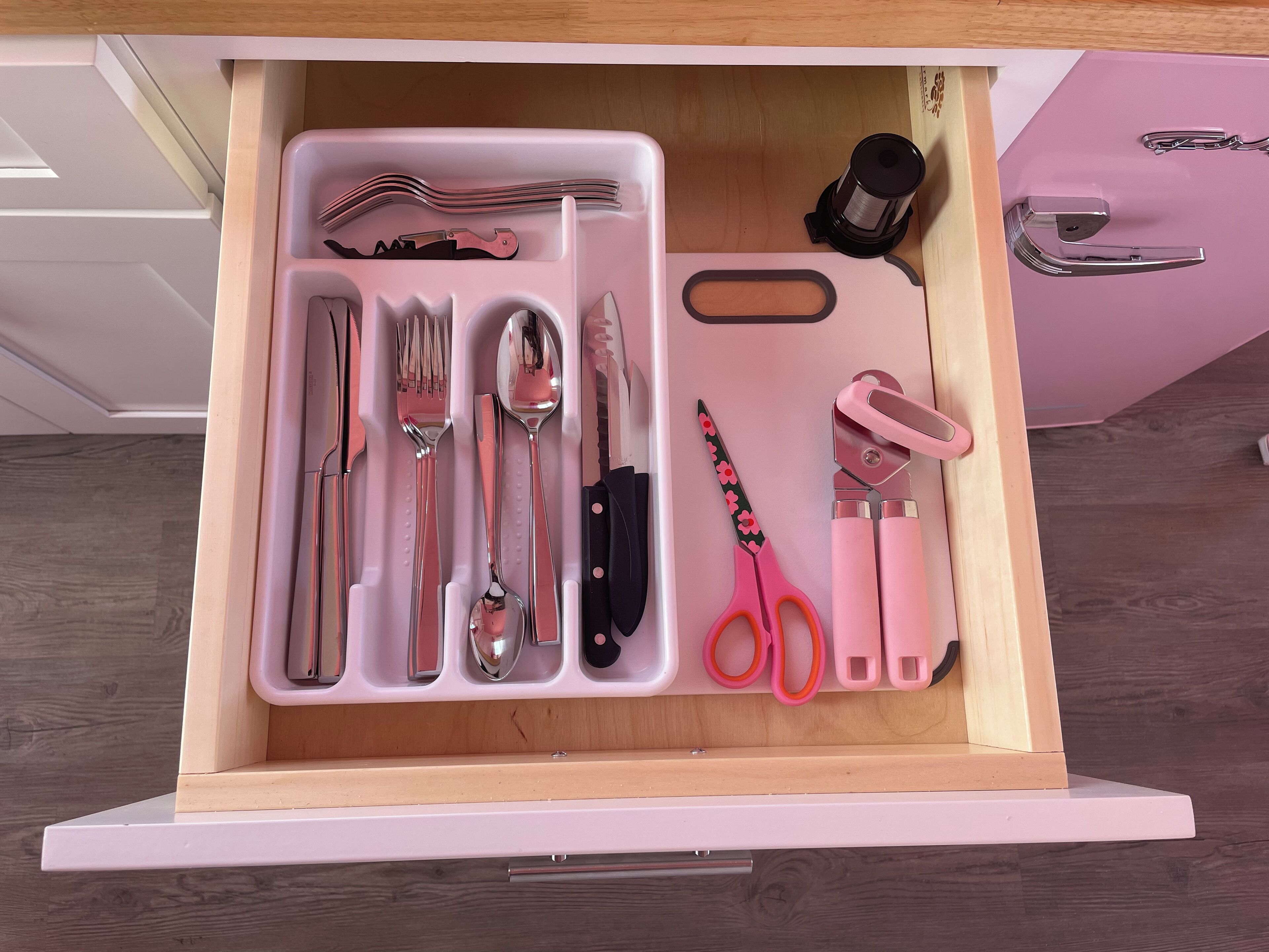 A drawer with neatly organized kitchen utensils including forks, knives, spoons, and scissors.