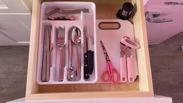 A drawer with neatly organized kitchen utensils including forks, knives, spoons, and scissors.