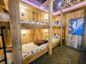 Une pièce rustique en bois, avec des lits superposés, une cheminée et un tableau représentant une cascade.