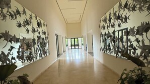 A hallway with a long corridor, walls adorned with dinosaur sculptures, and potted plants at the ends. - Modern Studio with Ocean View (Cruz de Huanacaxtle)